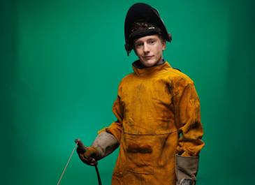Man wearing welding protective gear holding welding tool