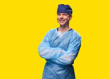 Man wearing scrubs smiling with arms folded across chest.