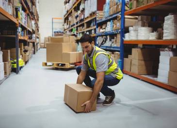 Person working in warehouse lifting a box from the floor.