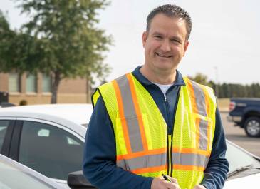 A man wearing a safety vest writes on notepad.