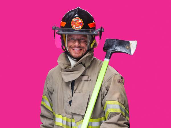 Man wearing firefighting helmet and jacket holding an ax