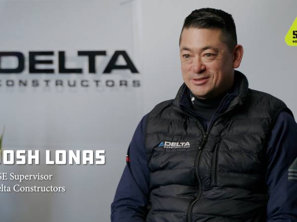 Man in Delta Constructors vest sitting with Delta Constructors name on the background and the Get Home Safe logo in the upper right hand corner