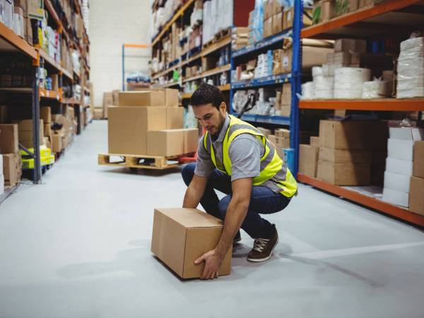 Person working in warehouse lifting a box from the floor.