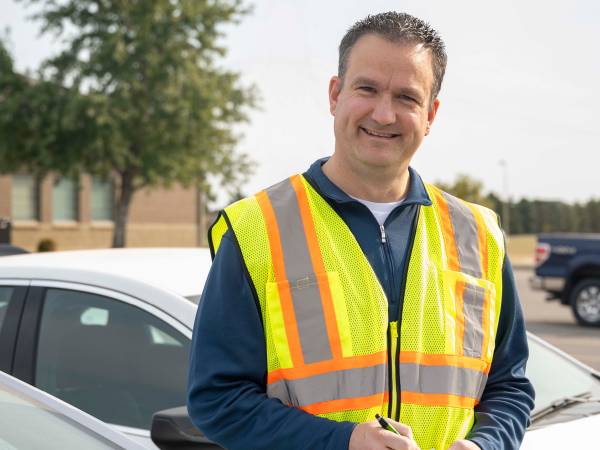 A man wearing a safety vest writes on notepad.