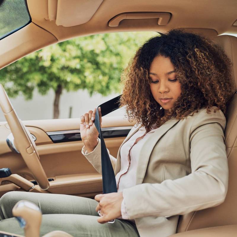 Woman sitting in the driver's seat buckling seat belt.