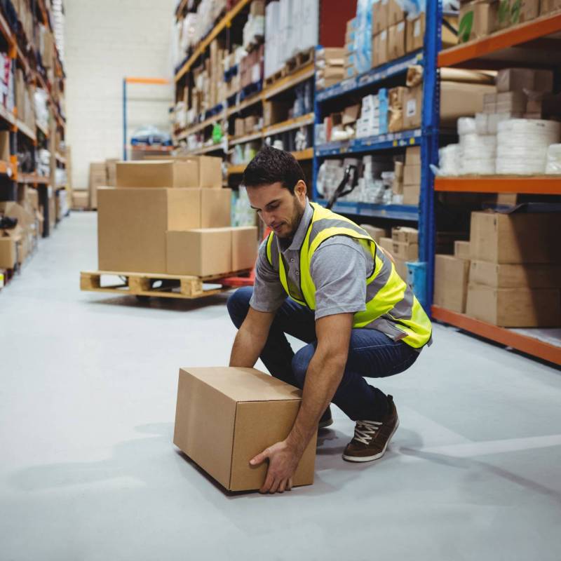 Person working in warehouse lifting a box from the floor.