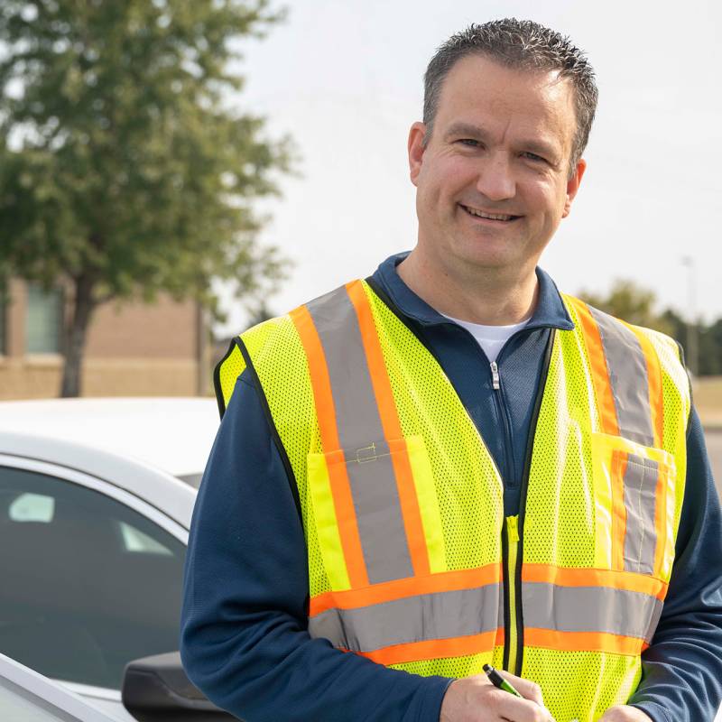 A man wearing a safety vest writes on notepad.