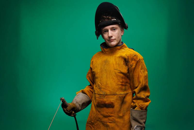 Man wearing welding protective gear holding welding tool